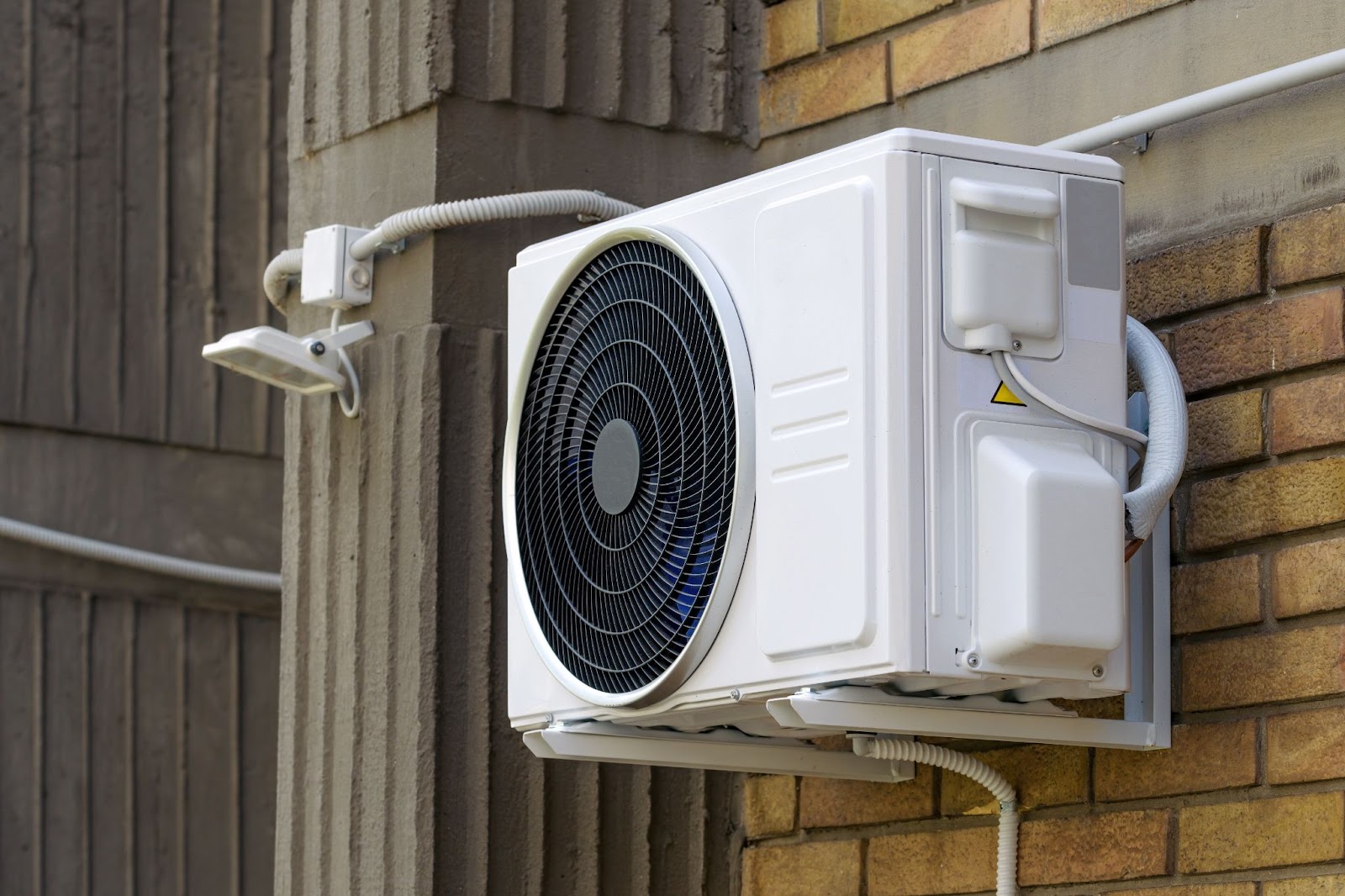 An outdoor unit of a ductless AC mounted on a building wall, showcasing its compact and efficient design. 