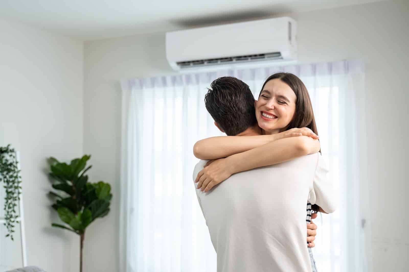 Two people embarrassing with an AC unit in the background. 