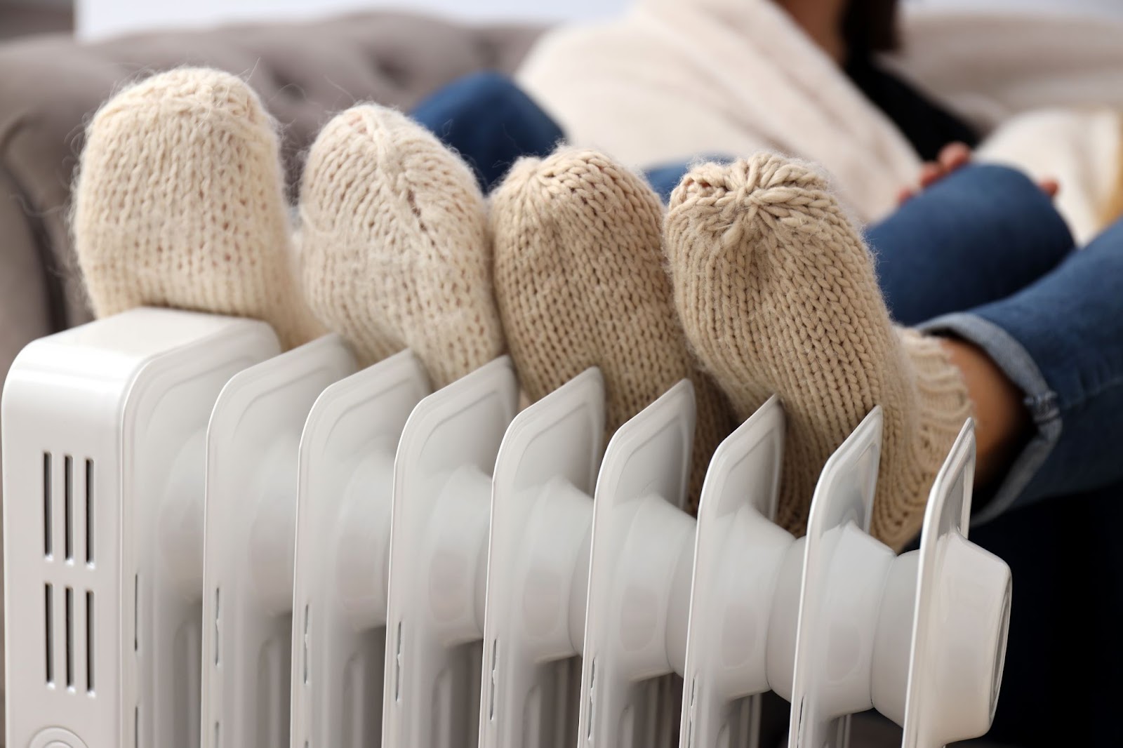 Two pairs of feet warming up on a heater, marking the beginning of the autumn and winter heating season