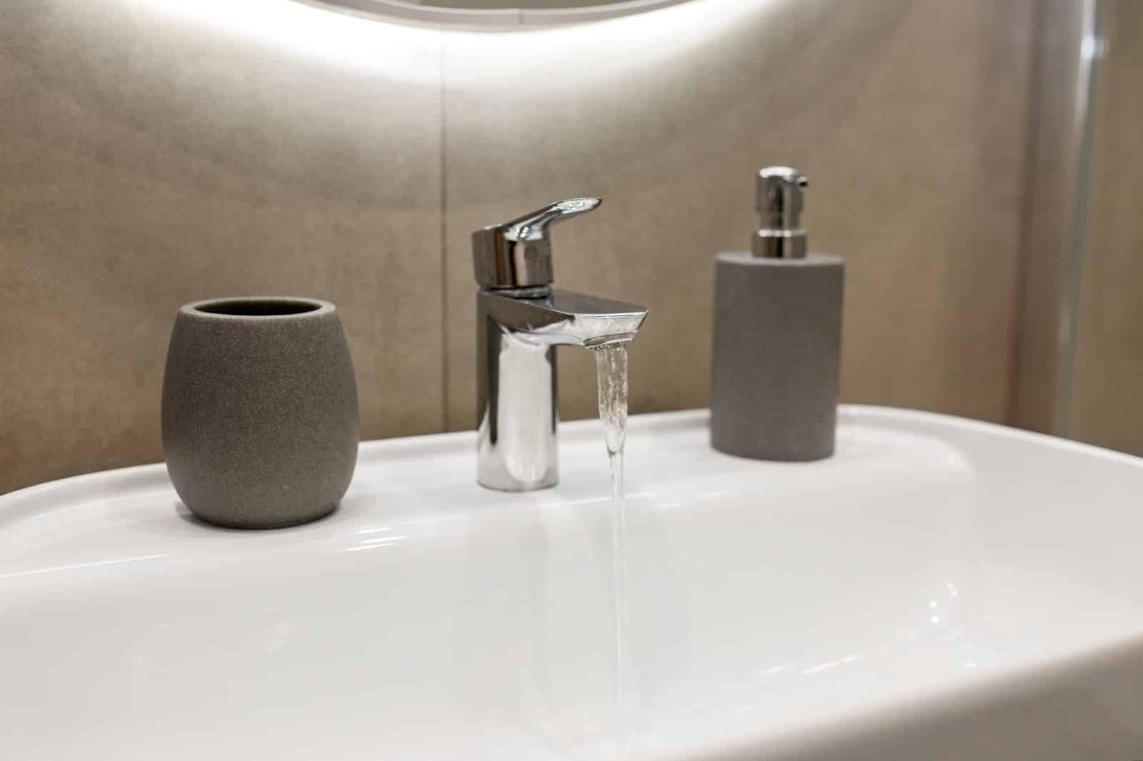 Sink faucet with a cup and soap dispenser. 