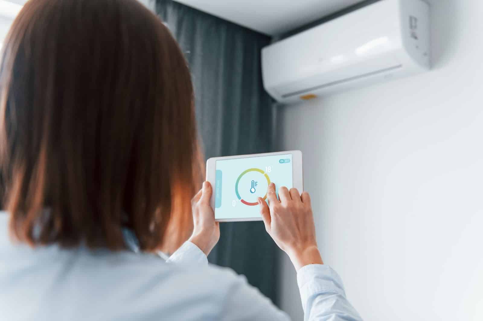 Woman adjusting the temperature using a tablet. 