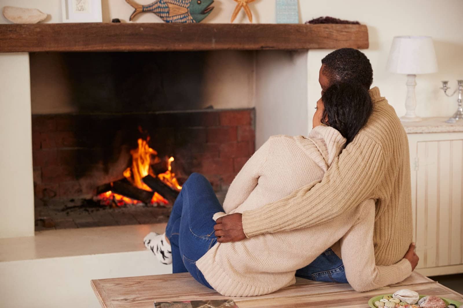 Couple sitting next to a fireplace. 