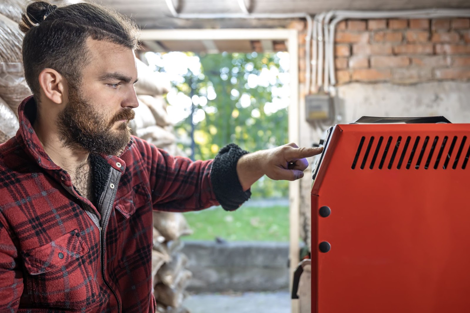 A man inspects his home furnace, carefully checking its components for maintenance. 
