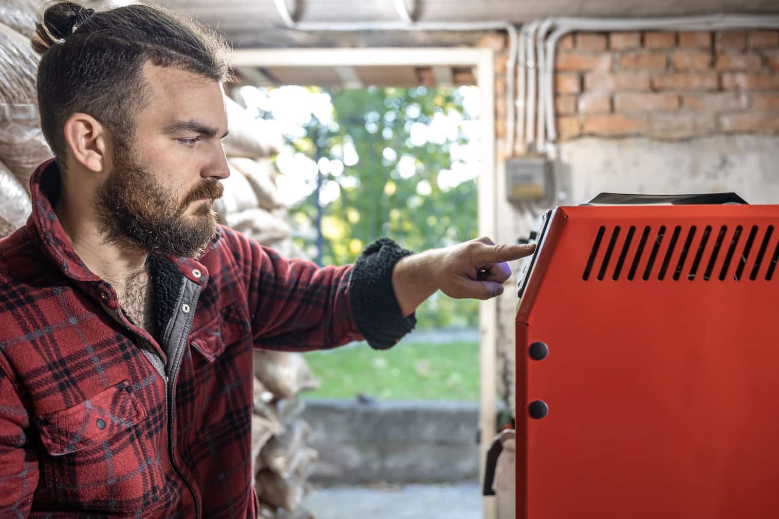 A man inspects his home furnace, carefully checking its components for maintenance. 